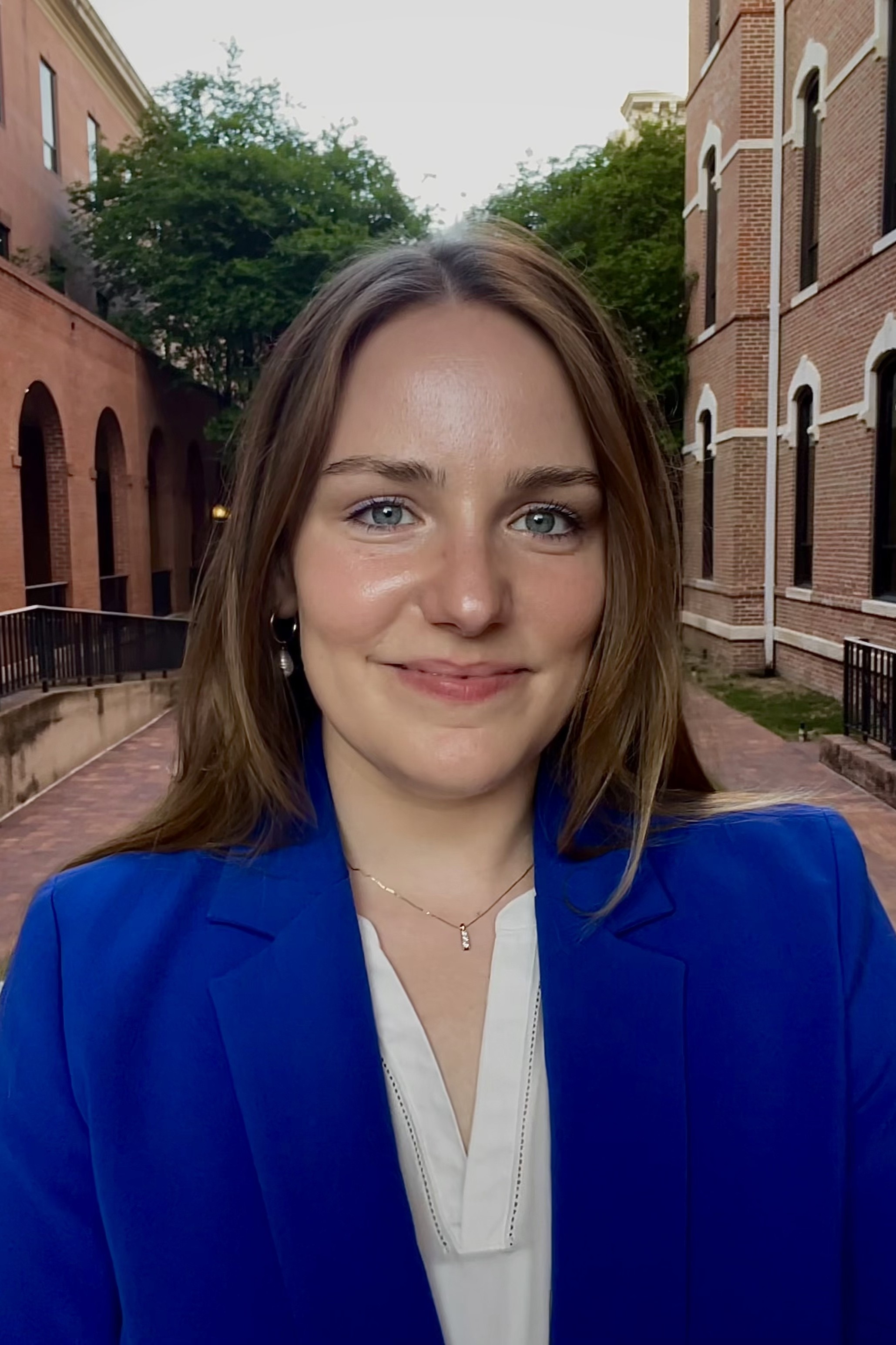 Headshot of female with long, light brown hair, white v neck shirt and bright blue blazer.