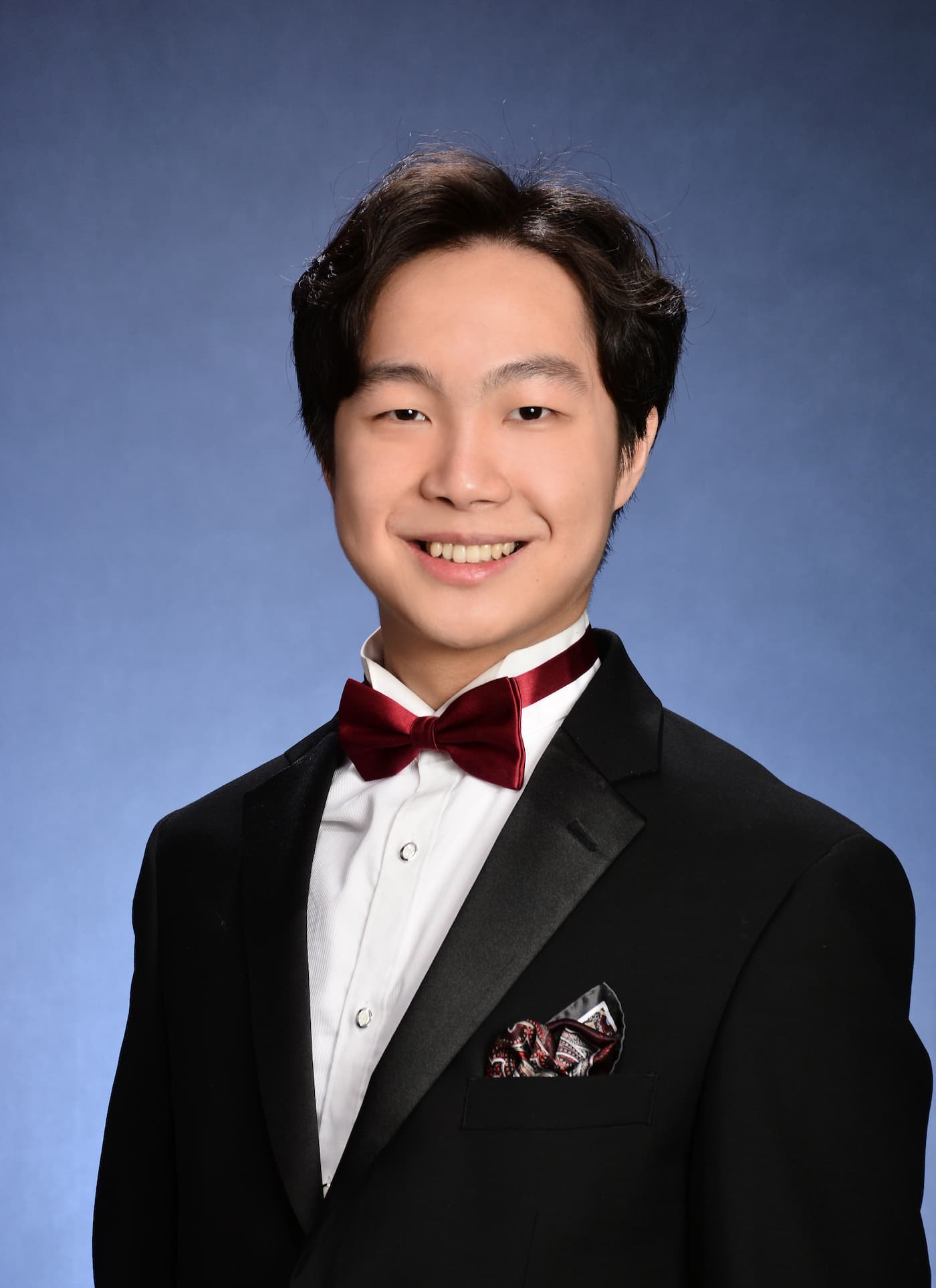 Henry Cao's smiles in a tux with a red tie in his professional headshot