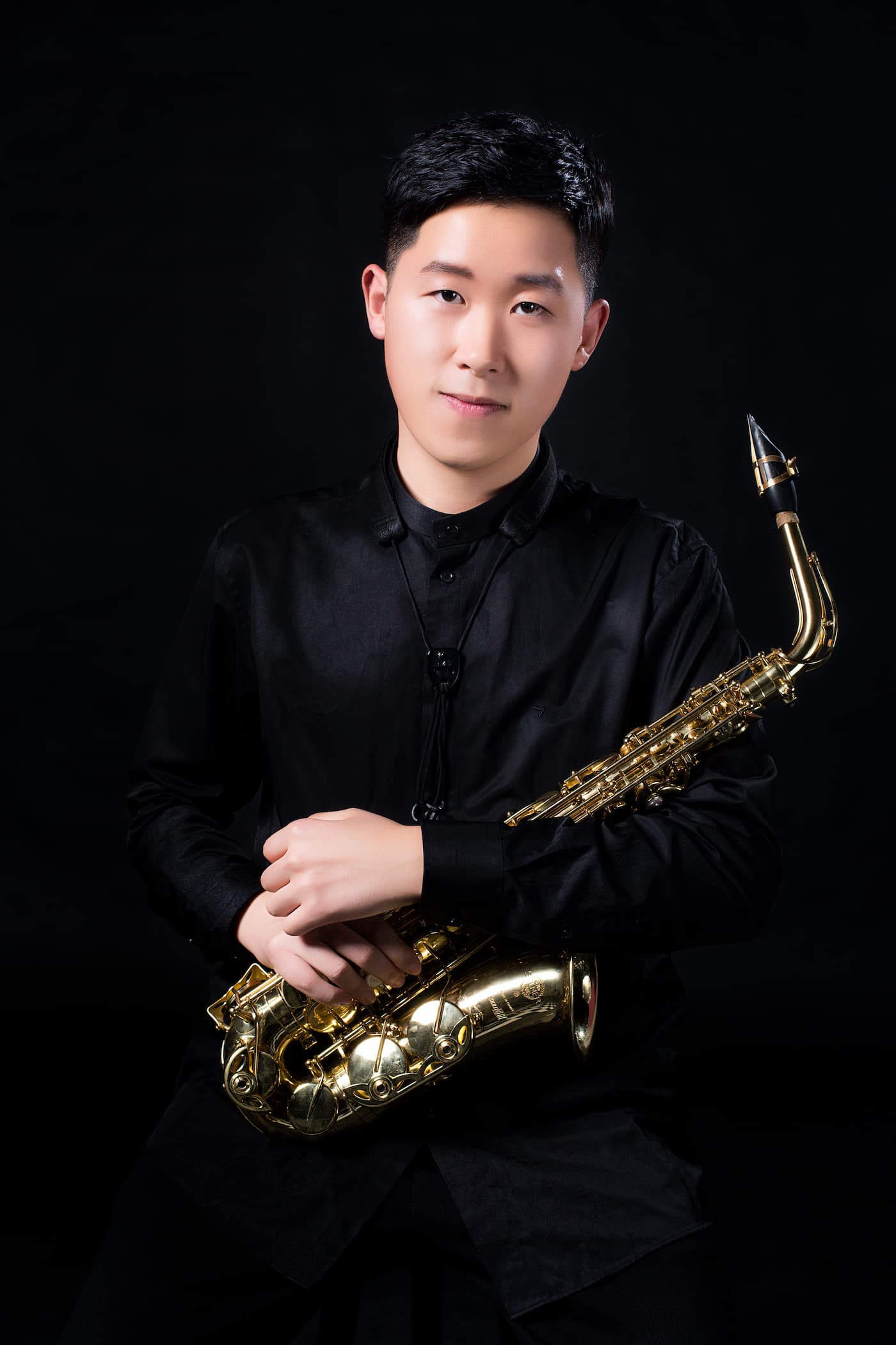 Jinkai Li holds an alto saxophone in his professional headshot