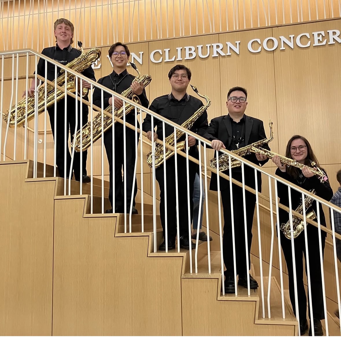The UNT Wind Symphony saxophone sections poses for a photo on the staircase at the Van Cliburn Concert Hall