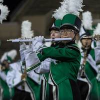 A flute player with a white plastic flute performs in full uniform
