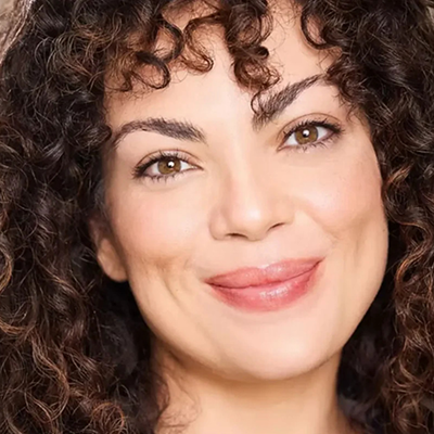  For the visually impaired: Giovannie is looking into the camera smiling with her mouth closed. She has long curly brown hair with brown eyes.