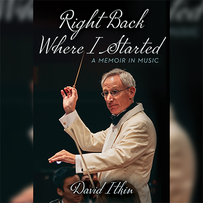 Professor Itkin is conducting looking to his left with his baton raised in his right hand. He is wearing a cream-colored jacket with a white shirt and black bow tie. He wears oval silver-colored eyeglasses.