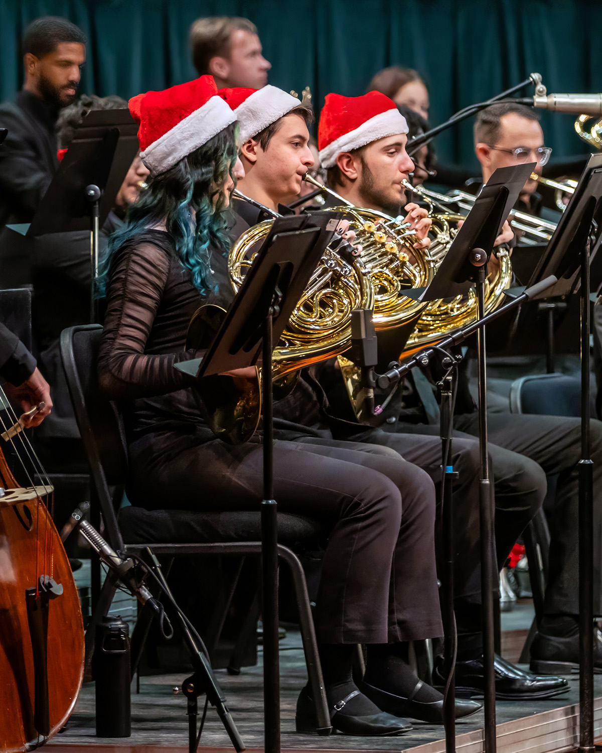 Horn players performing, seated, wearing Santa hats